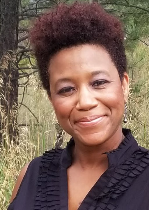 headshot of Naomi Williams, a young Black woman smiling at the camera wearing a v-neck ruffled black blouse