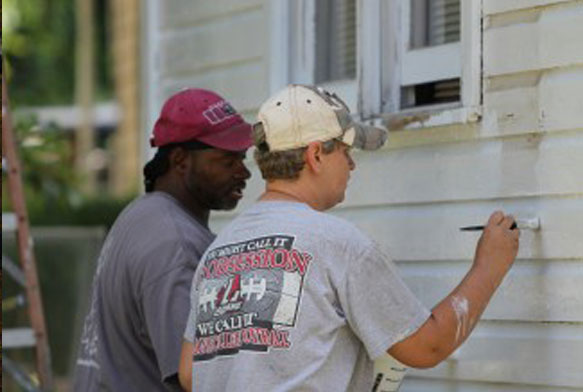 Volunteers help low-income homeowners paint their homes