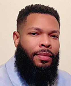 headshot of Nick Perry, a Black man with close cropped hair and a full beard looks at the camera
